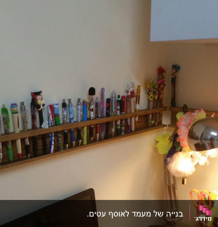 מדף עץ עם עטים צבעוניים על קיר